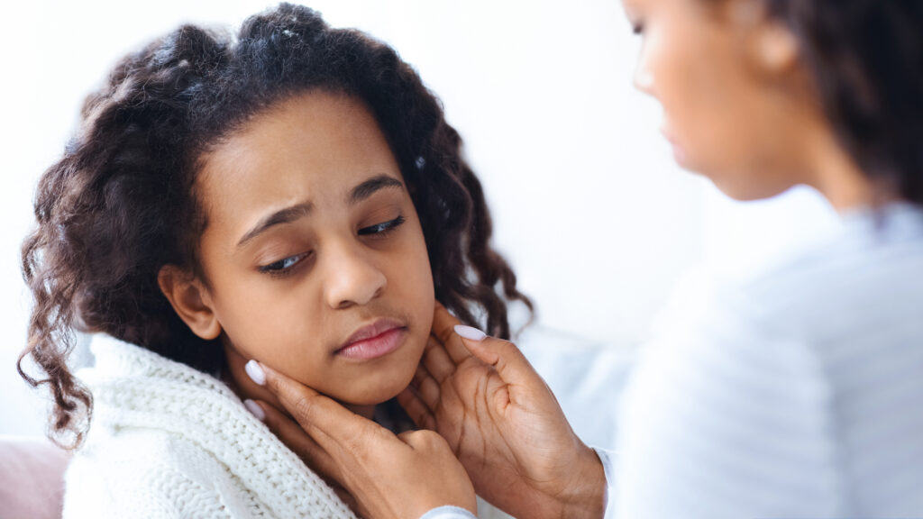 Child holding her throat with sore throat symptoms