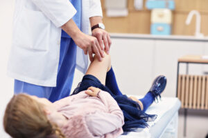 Provider examining a toddler's hip for transient synovitis in a pediatric urgent care setting